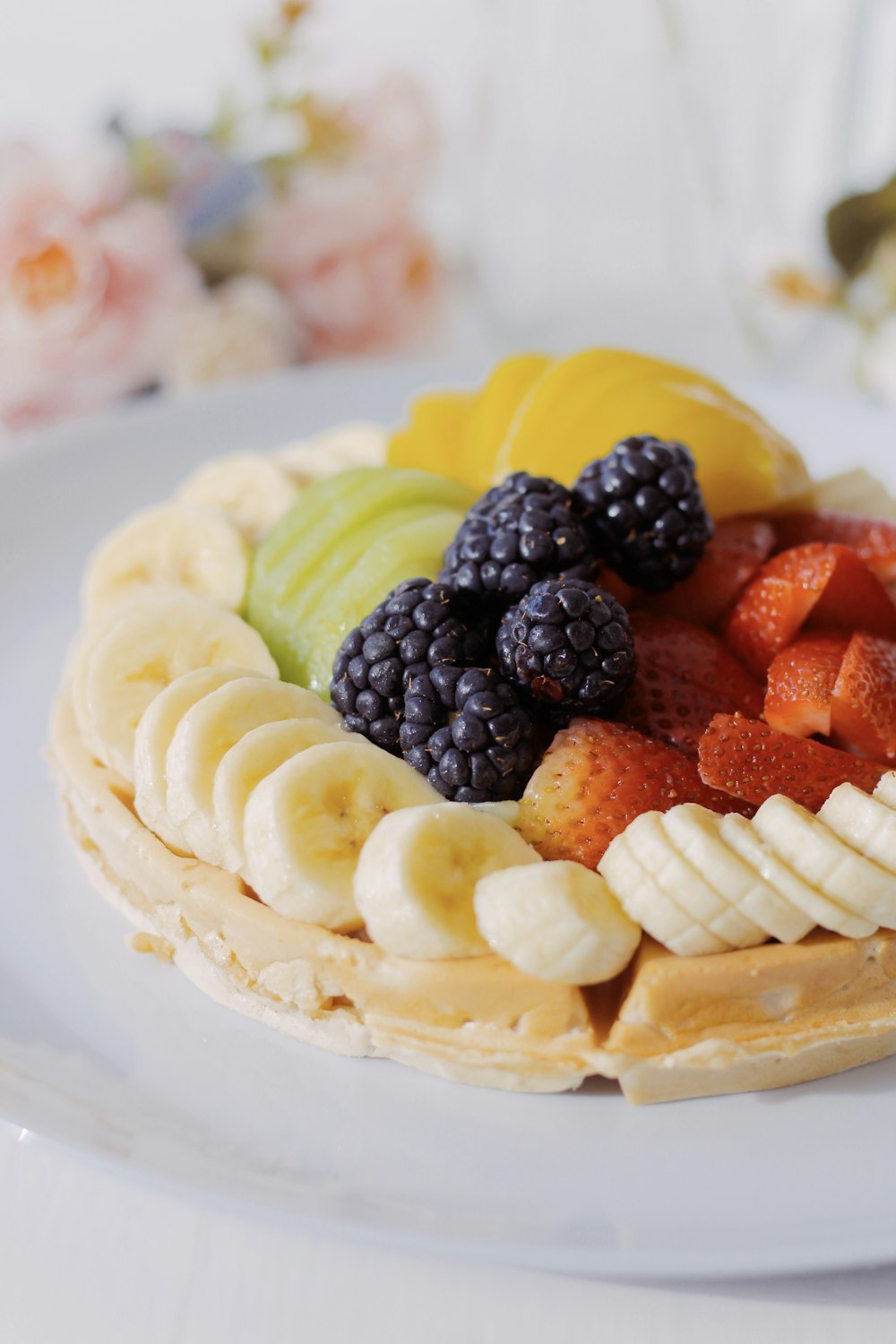 a white plate topped with a waffle covered in fruit