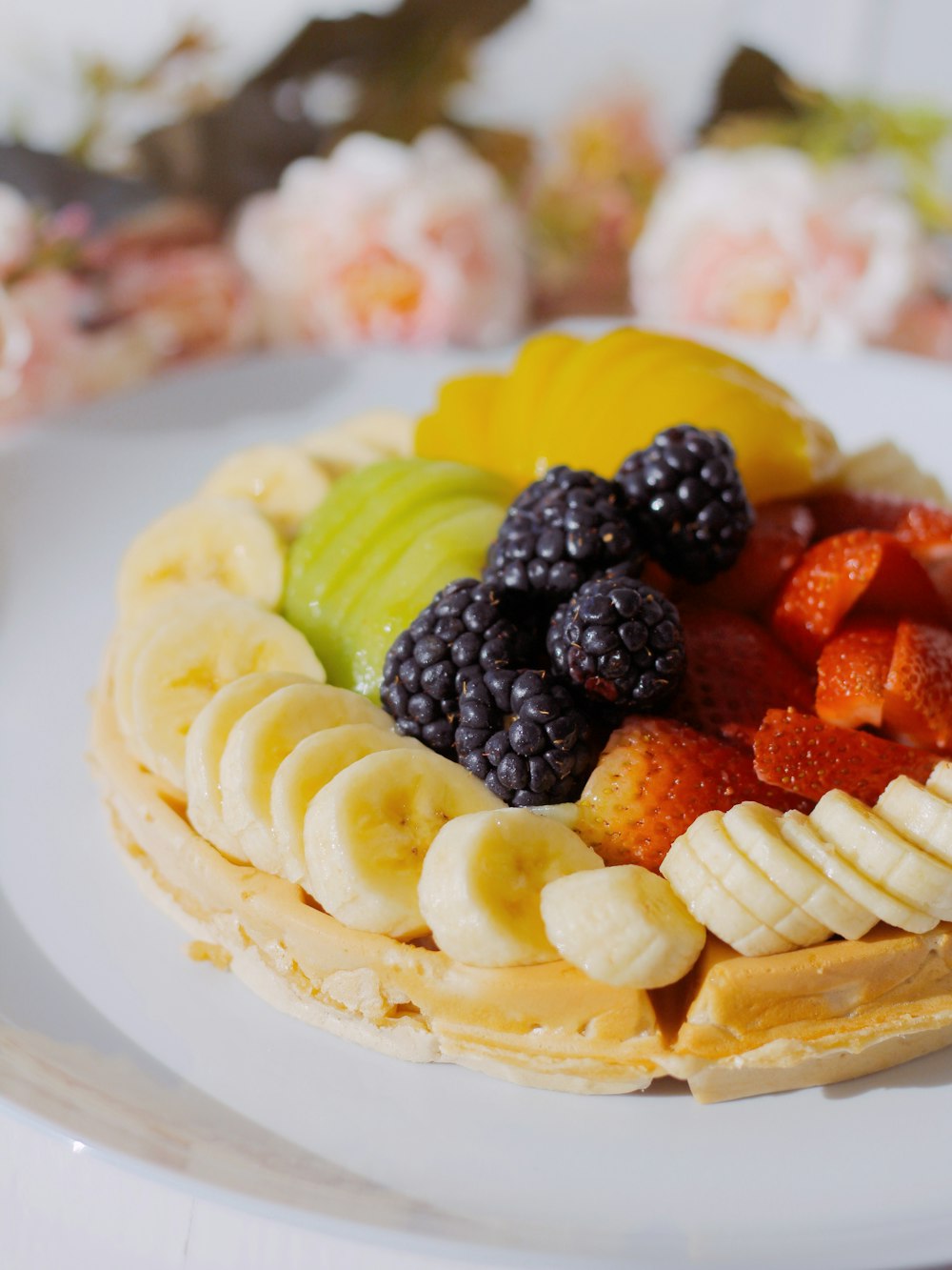 a white plate topped with a waffle covered in fruit