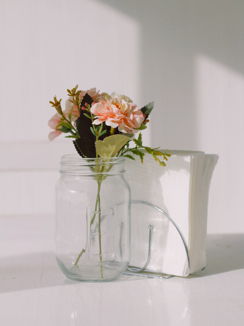 a glass jar with flowers in it sitting on a table