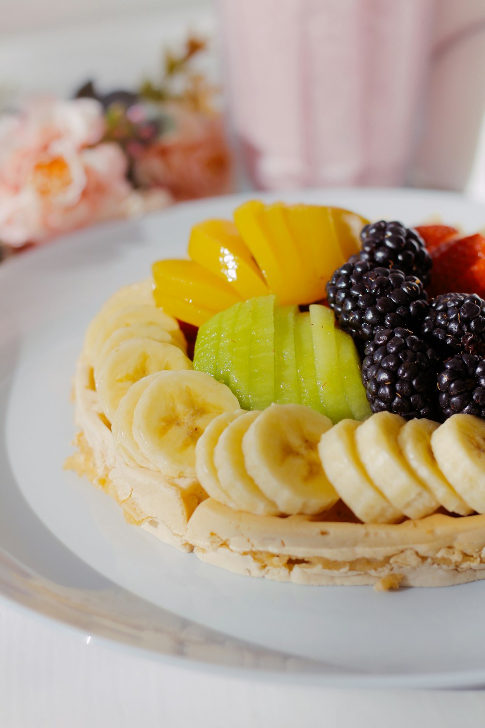 a white plate topped with a waffle covered in fruit