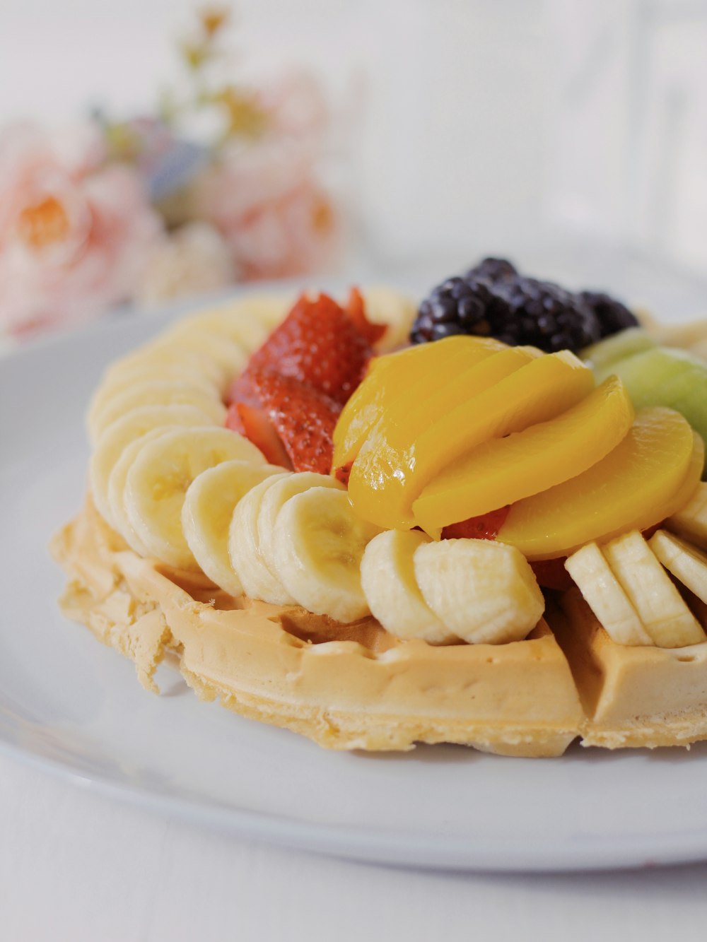 a white plate topped with waffles covered in fruit