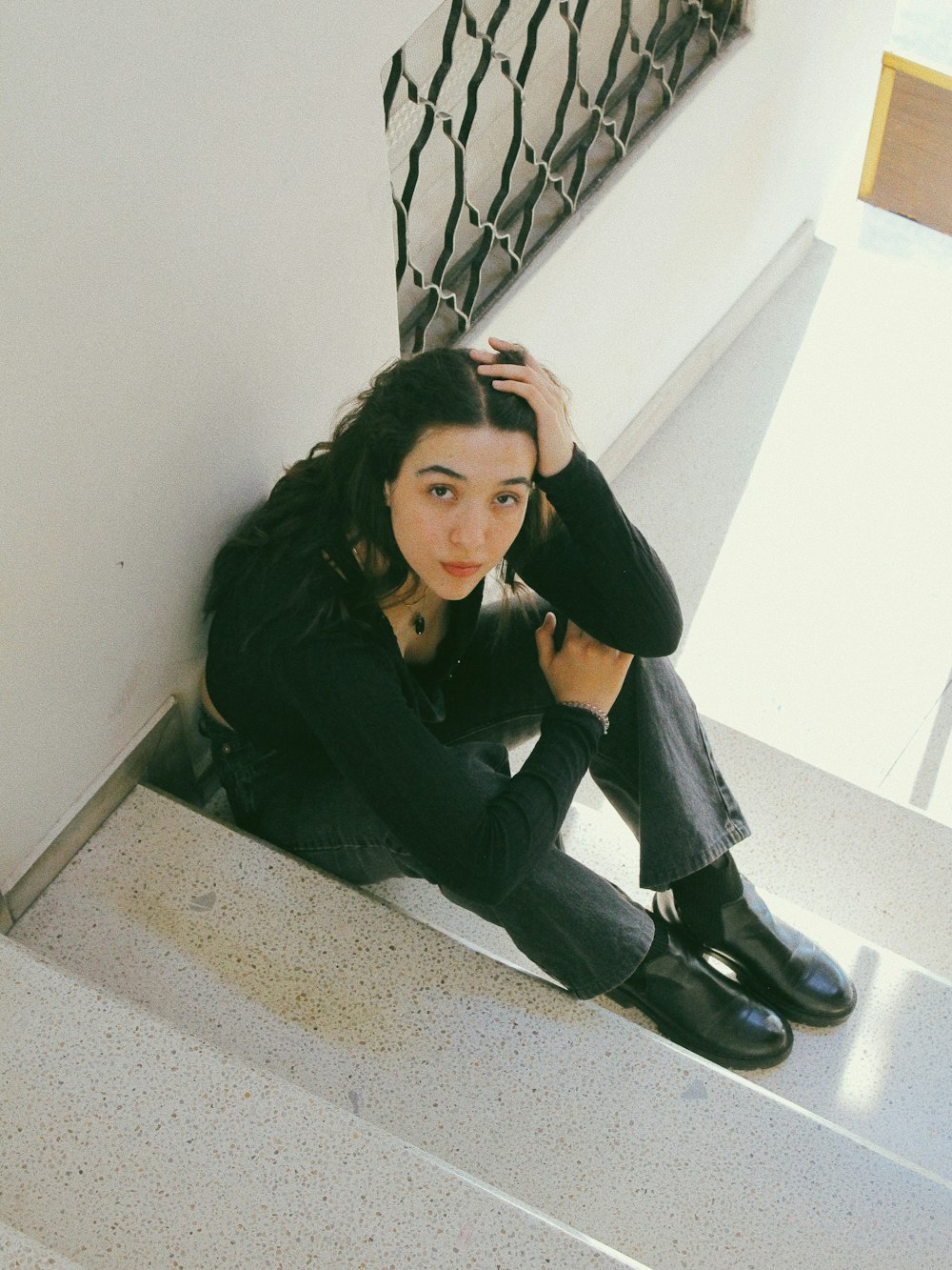 a woman is sitting on the stairs with her hand on her head