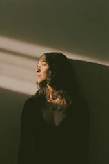 a woman standing against a wall with her eyes closed