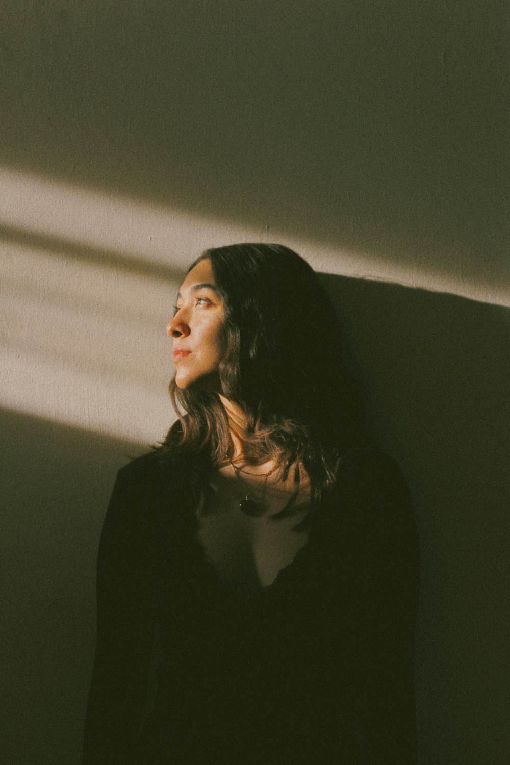 a woman standing against a wall with her eyes closed