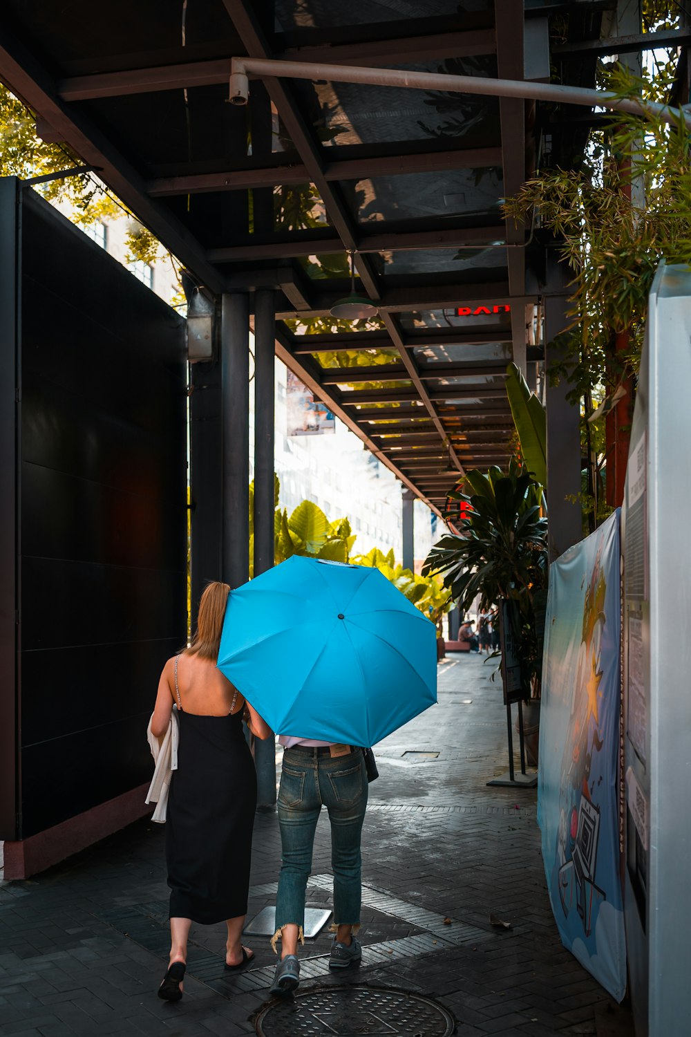 a couple of women walking down a street holding an umbrella