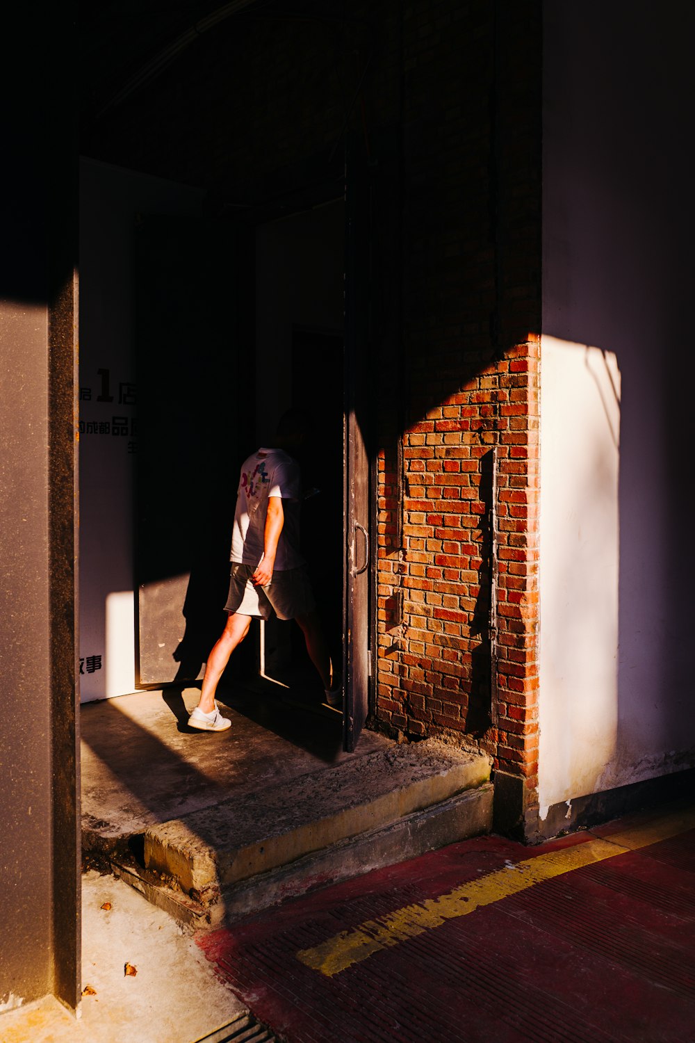 a man walking out of a doorway onto a sidewalk