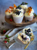 Close-up of a colorful vegan cupcake topped with fresh berries on a rustic wooden table