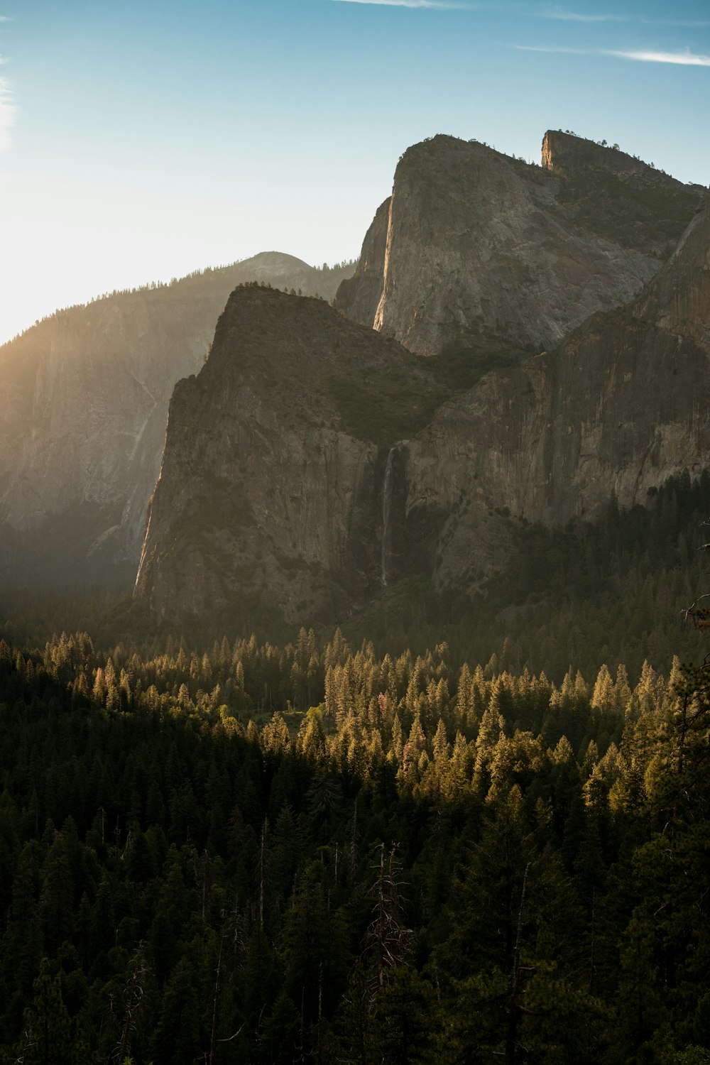 the sun is shining on the mountains and trees