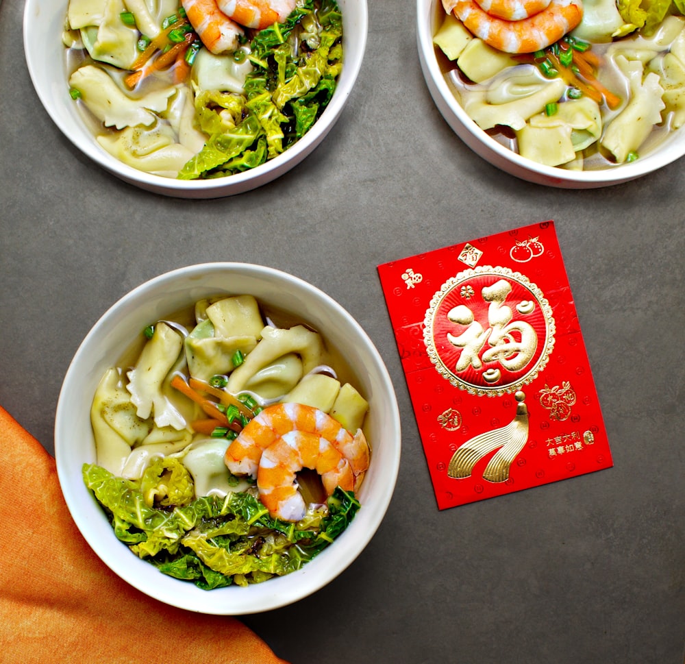 three bowls of food on a table with a red packet