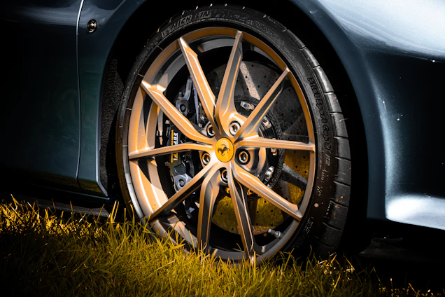 Close-up of a sleek alloy wheel on a luxury sports car under soft lighting.