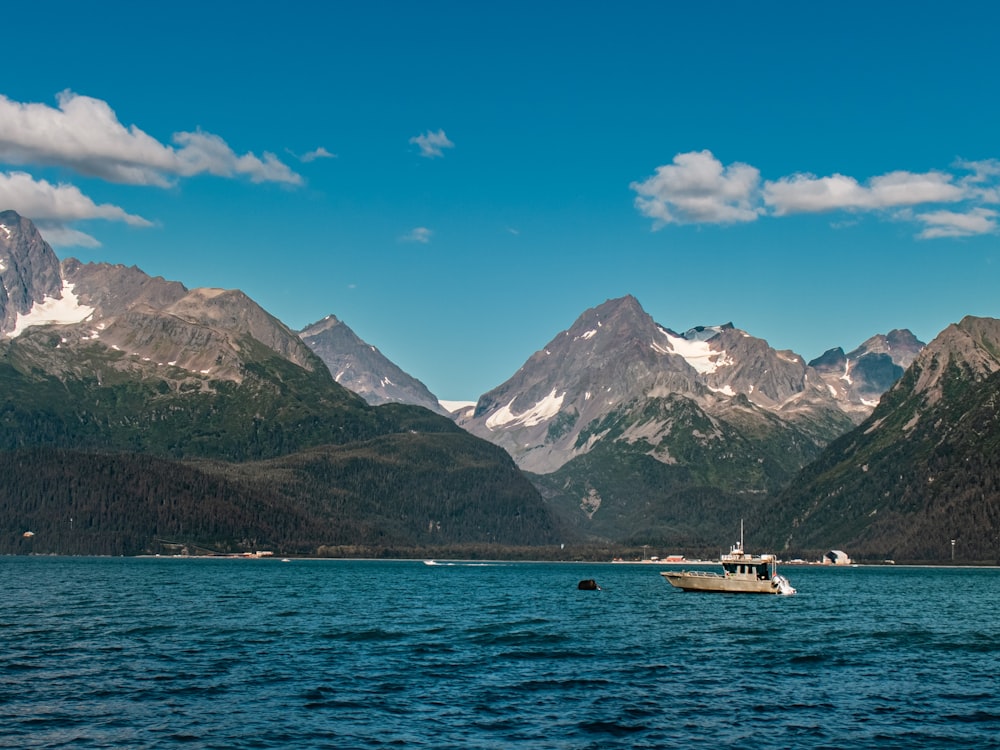 a boat floating on a lake surrounded by mountains