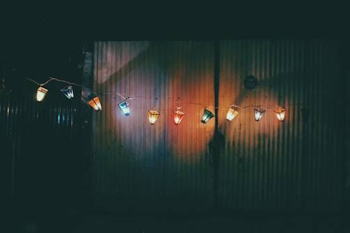 A row of colorful Luminara LED lights hanging in a trendy urban loft setting.