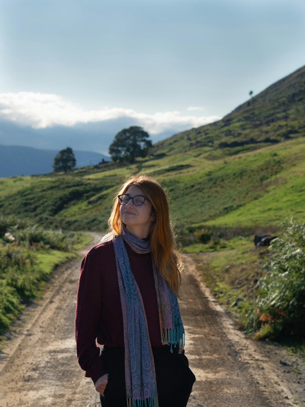 a woman standing in the middle of a dirt road