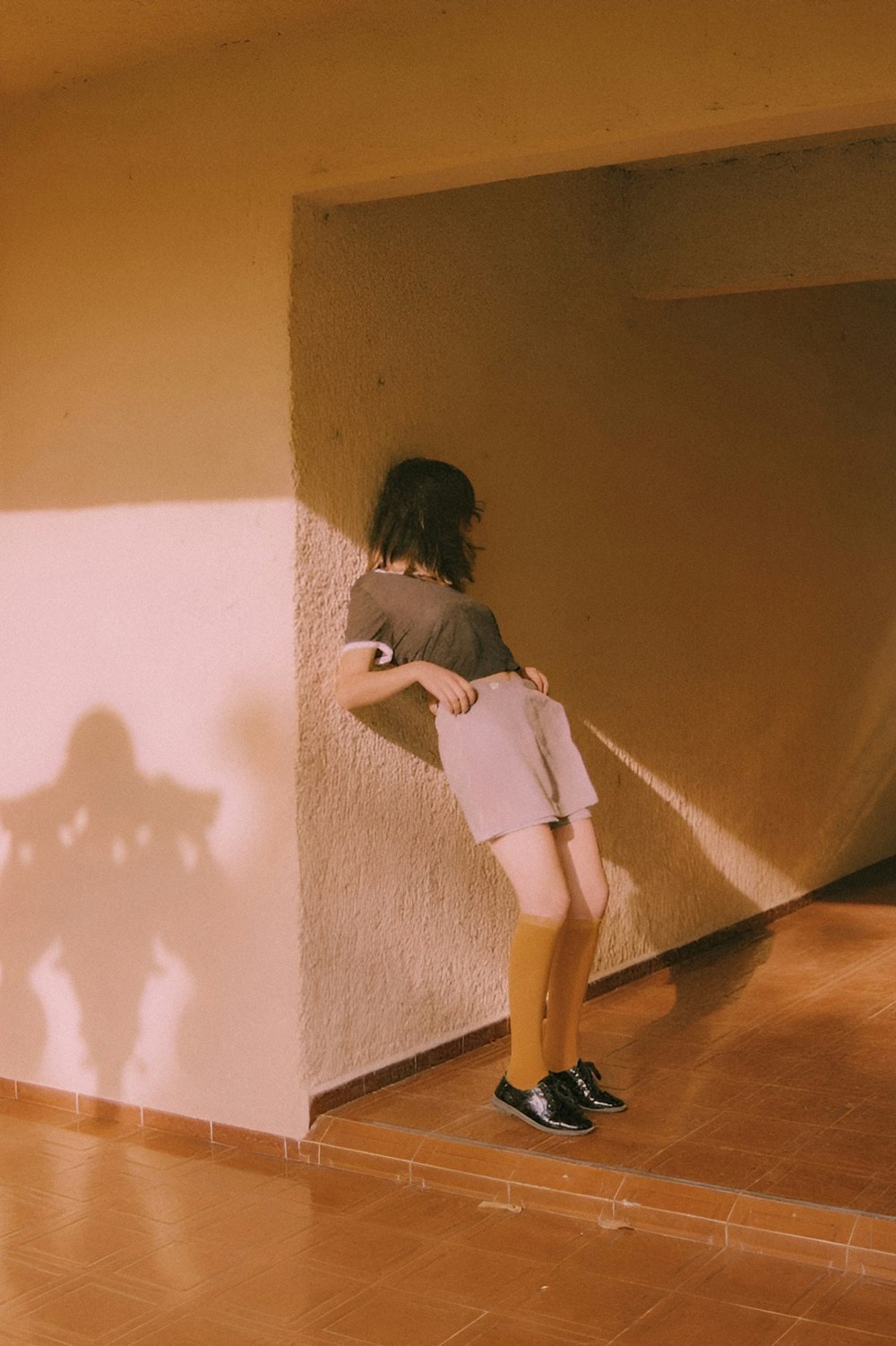a woman standing next to a wall with her shadow on the wall