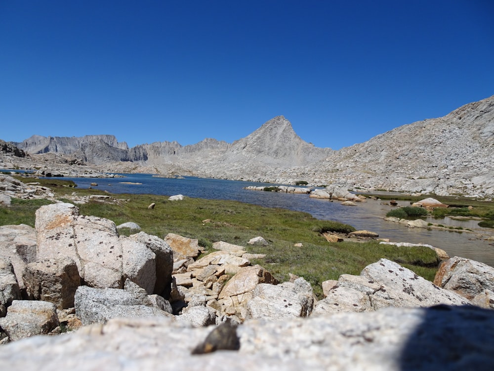 a view of a lake surrounded by rocks and grass