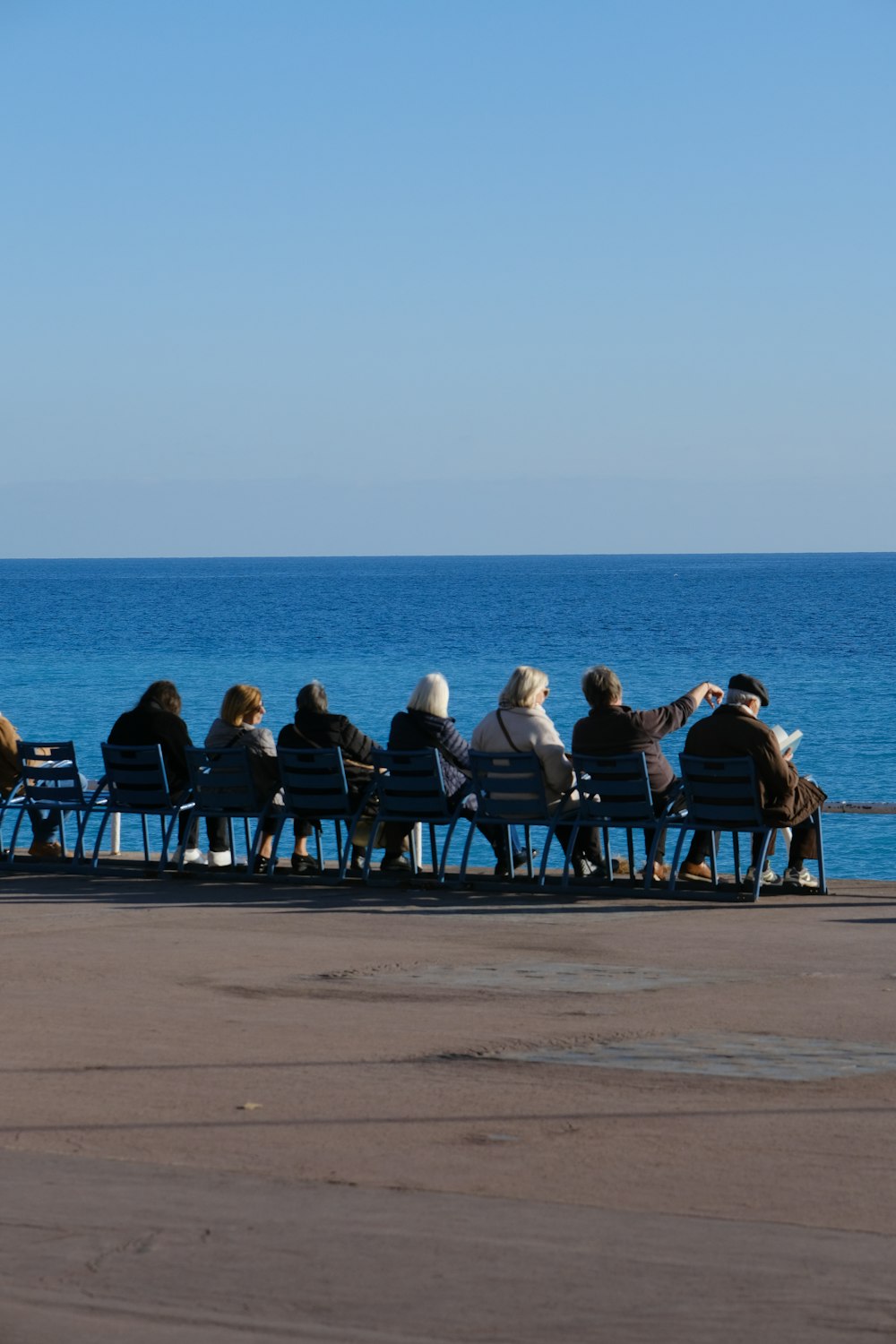 海の隣のベンチの上に座っている人々のグループ