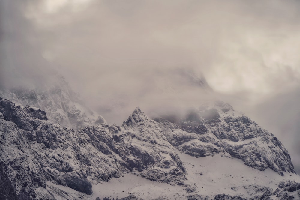 a mountain covered in snow under a cloudy sky