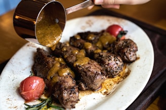 A slow-motion frame of a chef drizzling rich sauce over a perfectly grilled steak, with deep shadows and highlights.