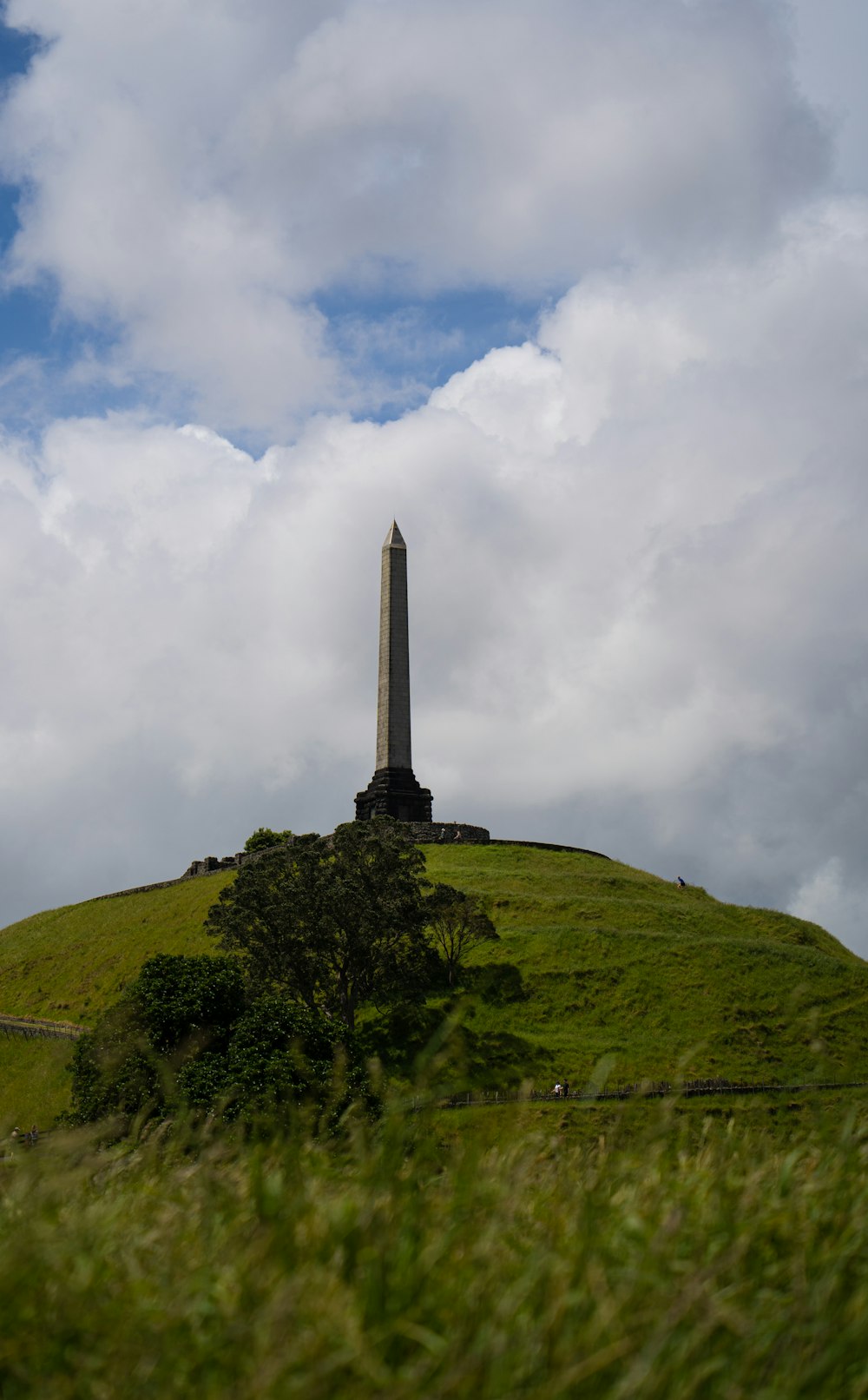 a tall monument on top of a green hill
