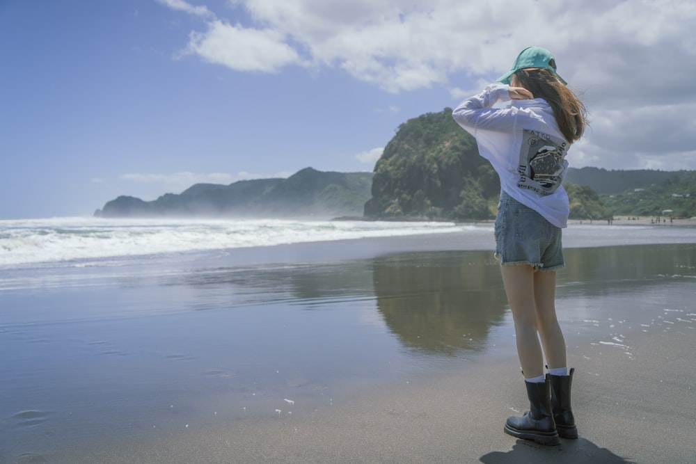 uma mulher em pé em uma praia ao lado do oceano