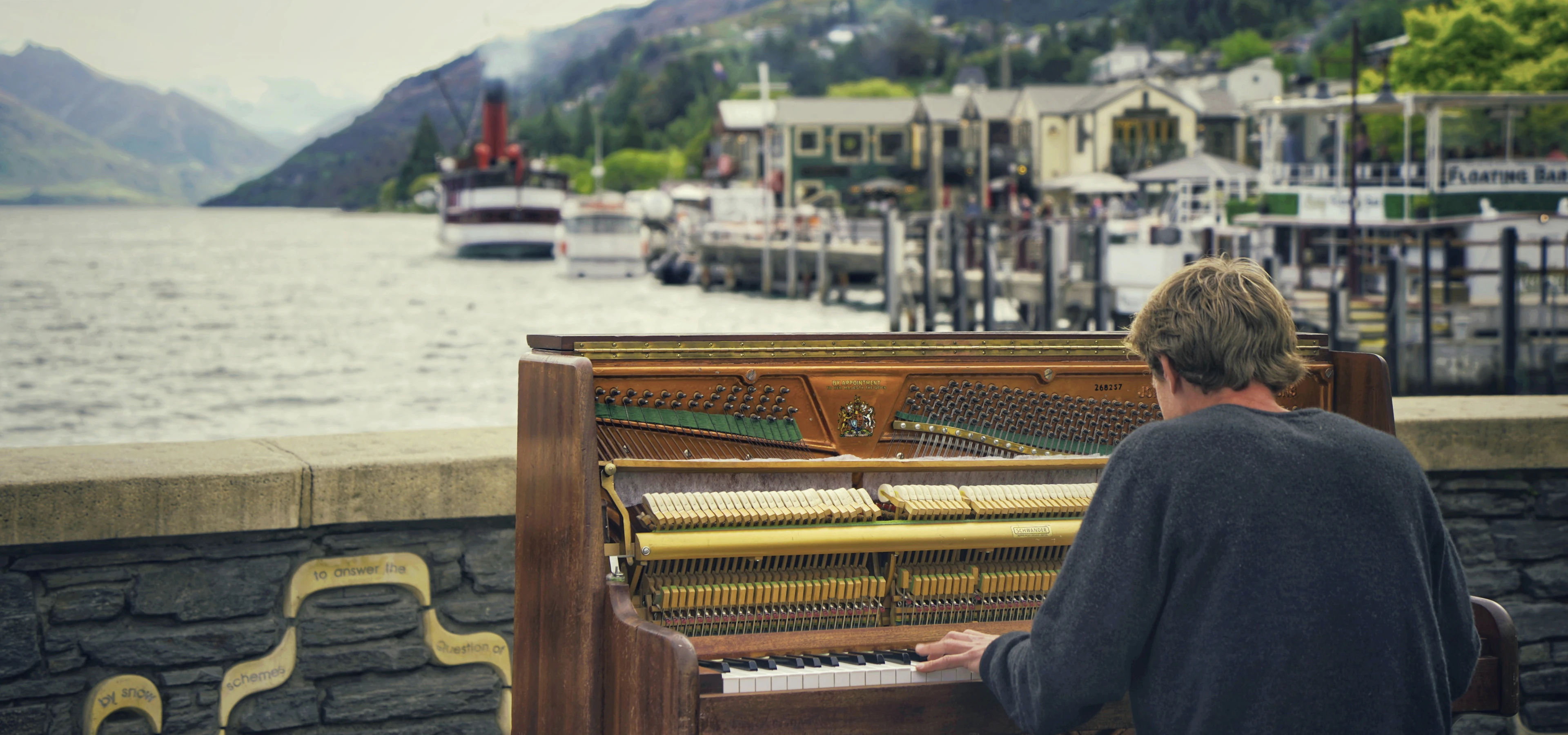A piano played outdoors on the lakefront at Queenstown, a steamer at the wharf