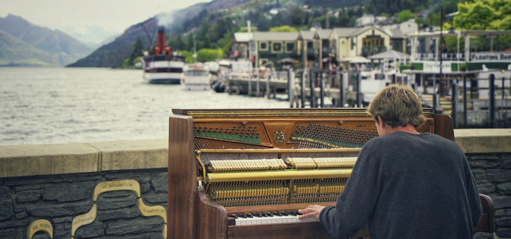 a man sitting at a piano near a body of water