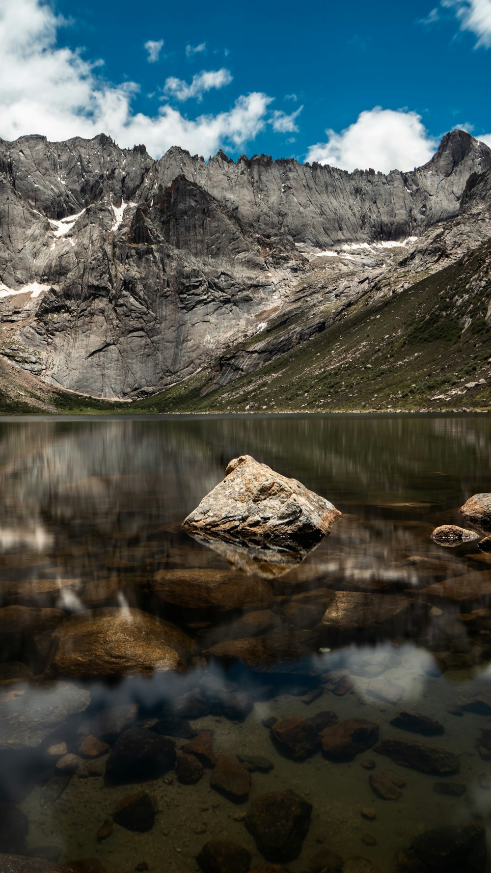 a lake surrounded by mountains and rocks under a blue sky