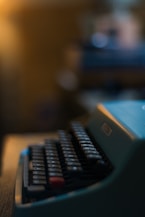 Close-up of hands typing on a vintage typewriter with amber light casting shadows.