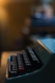 Close-up of hands typing on an old-fashioned keyboard with warm lighting.