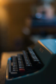 Close-up of hands typing on a vintage typewriter with soft sunlight.