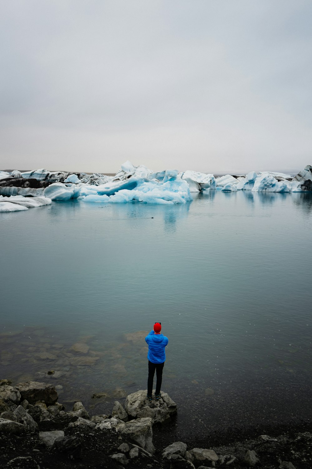 una persona in piedi su una roccia vicino a uno specchio d'acqua
