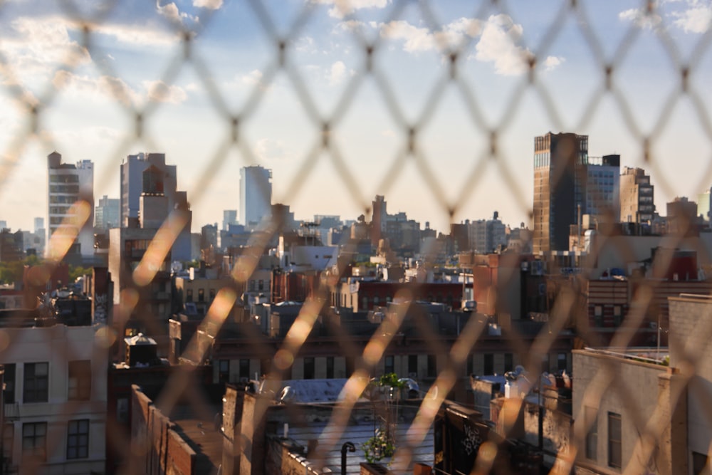 a view of a city through a chain link fence