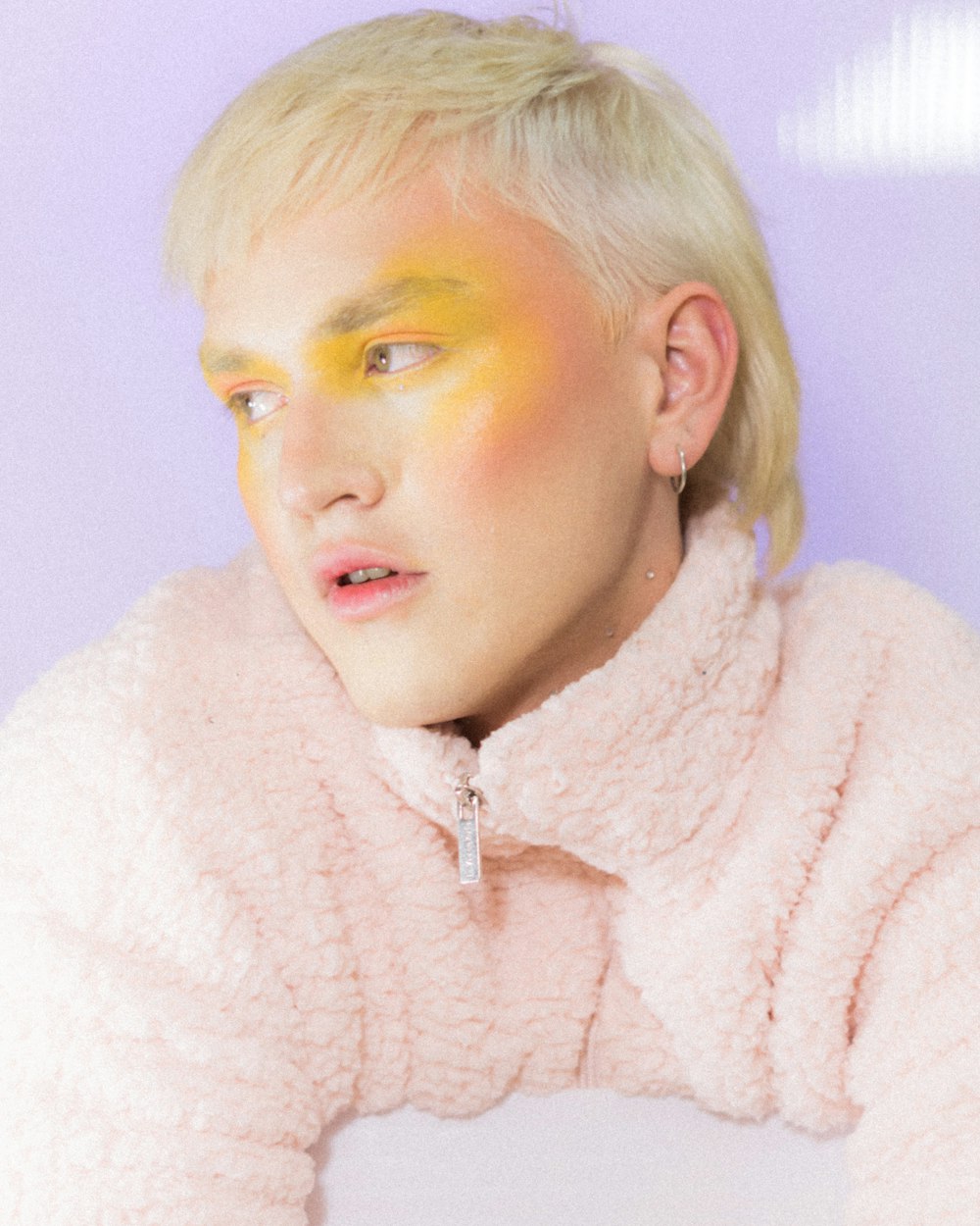 a woman with yellow makeup and a pink coat