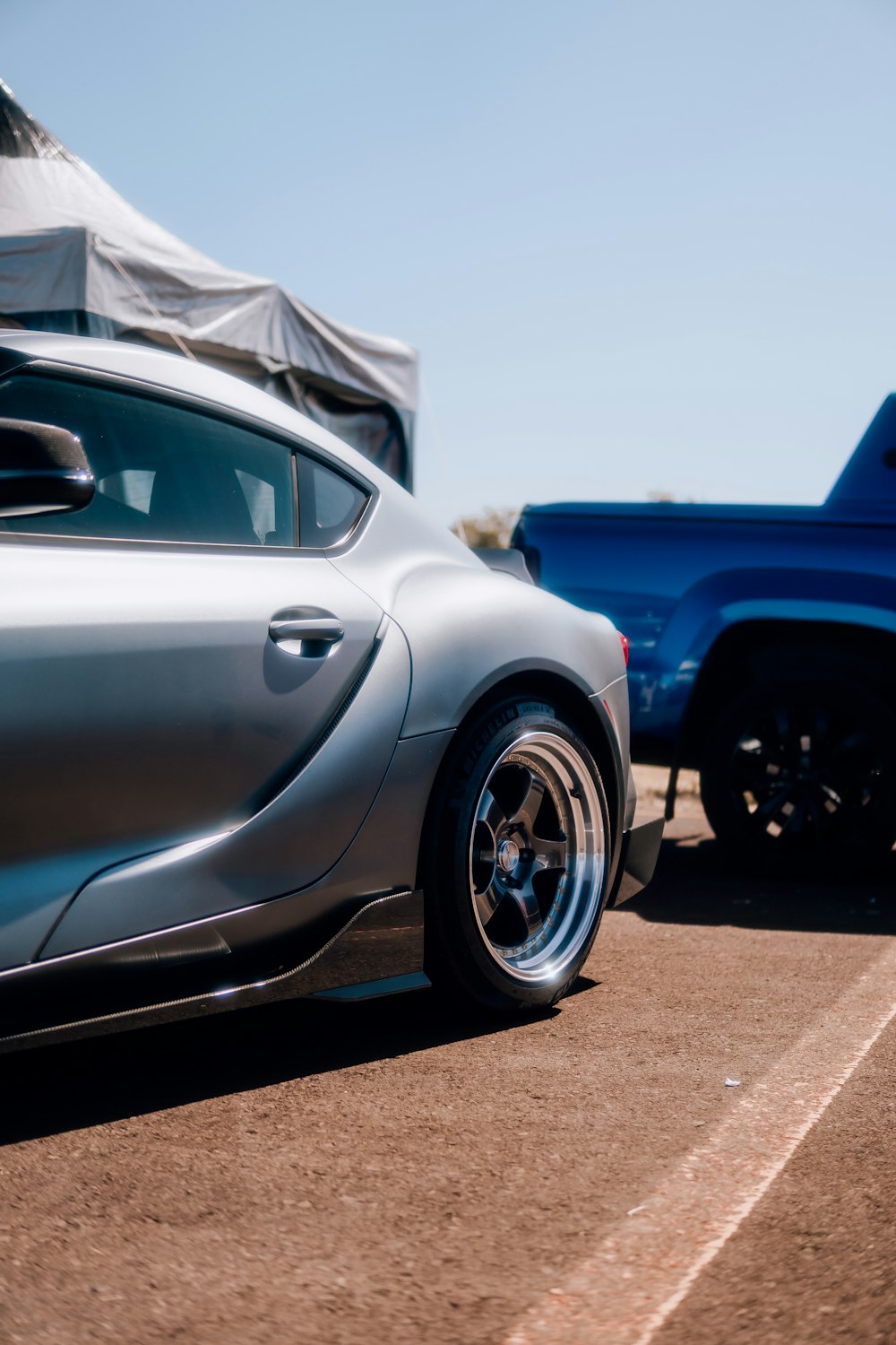 a silver sports car parked next to a blue truck