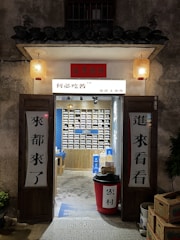 A warm, inviting storefront with wooden beams, colorful textiles hanging, and vintage lanterns glowing softly.