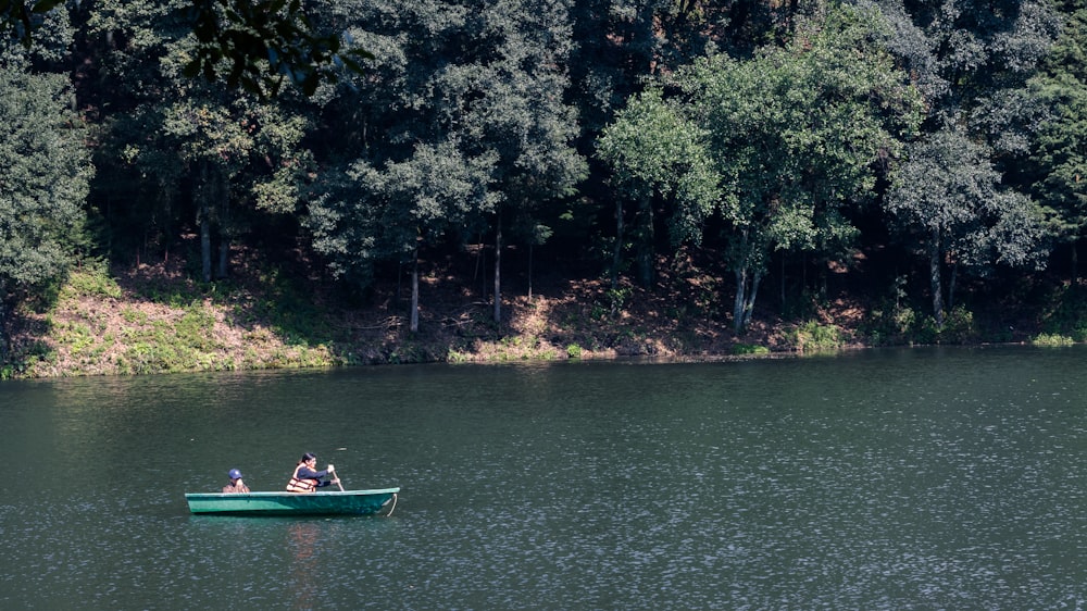 two people in a small green boat on a lake