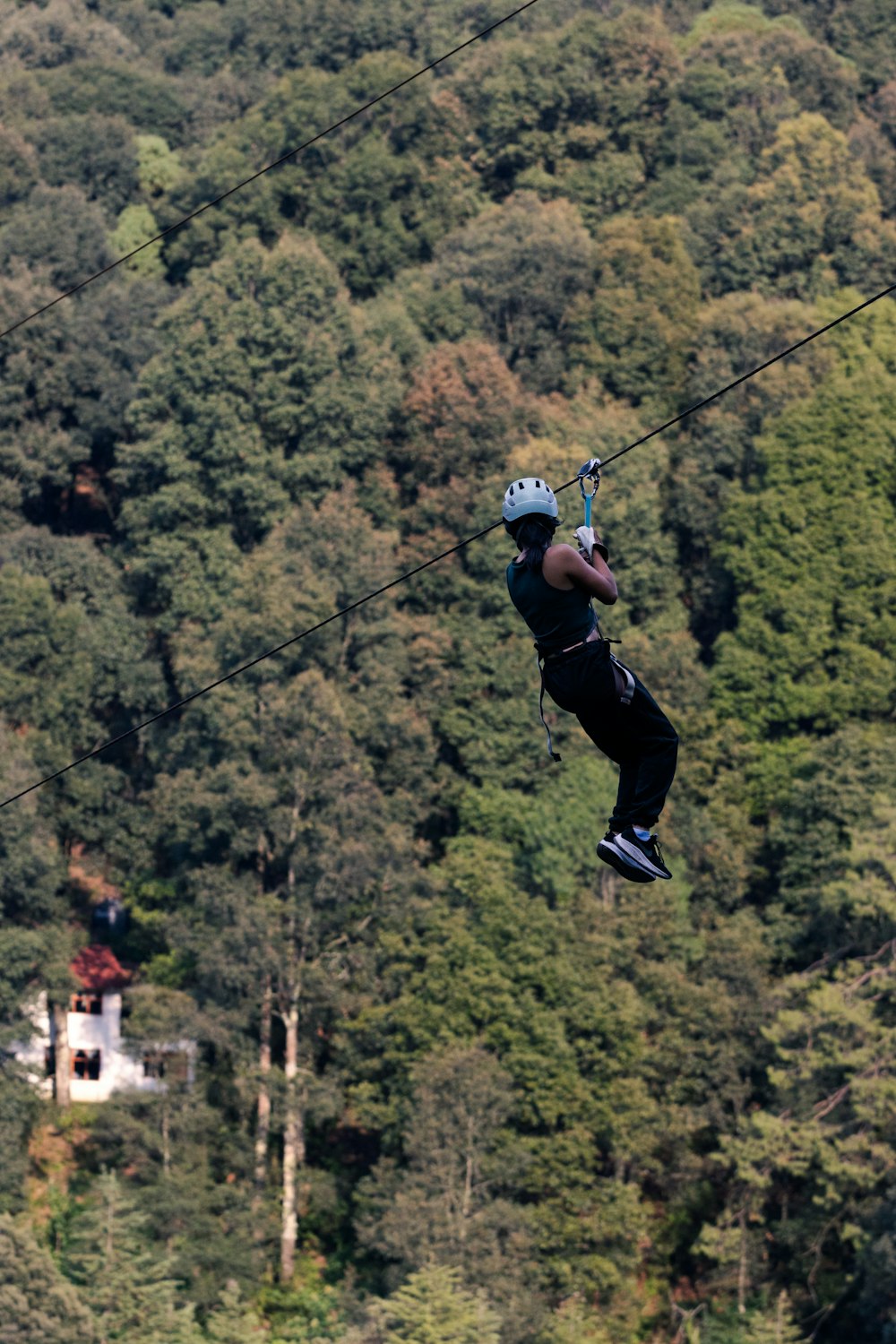 a man riding a zip line over a lush green forest