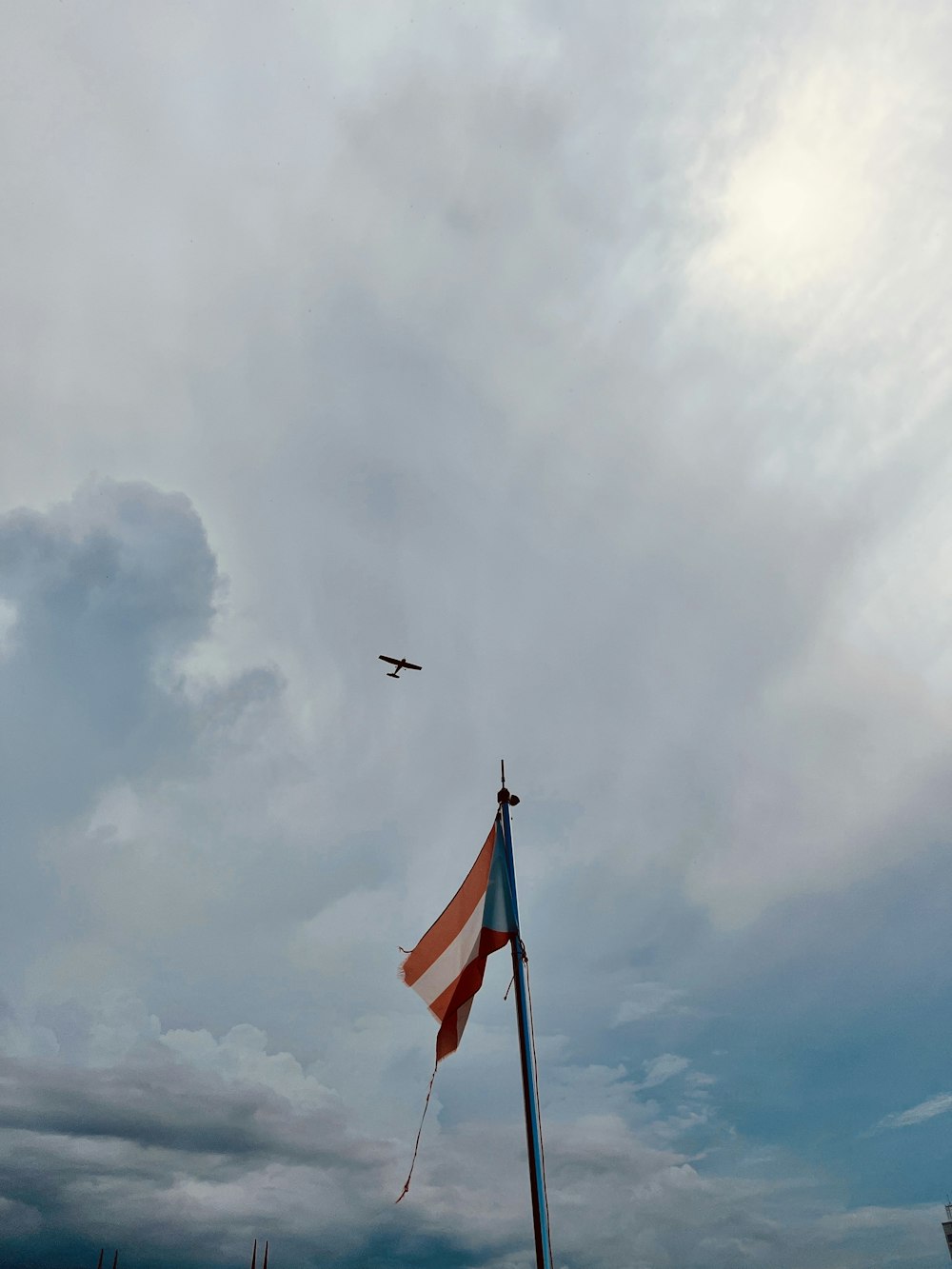 an airplane flying over a flag on a cloudy day