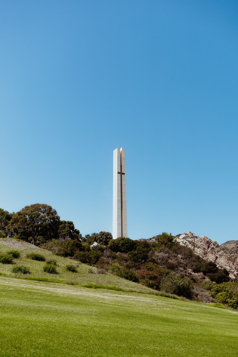 a tall monument on top of a lush green hillside