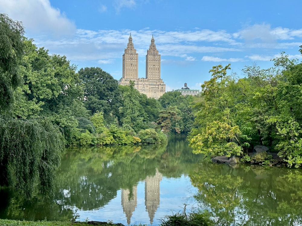 un lac entouré d’arbres avec un grand bâtiment en arrière-plan