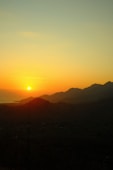 the sun is setting over a mountain range