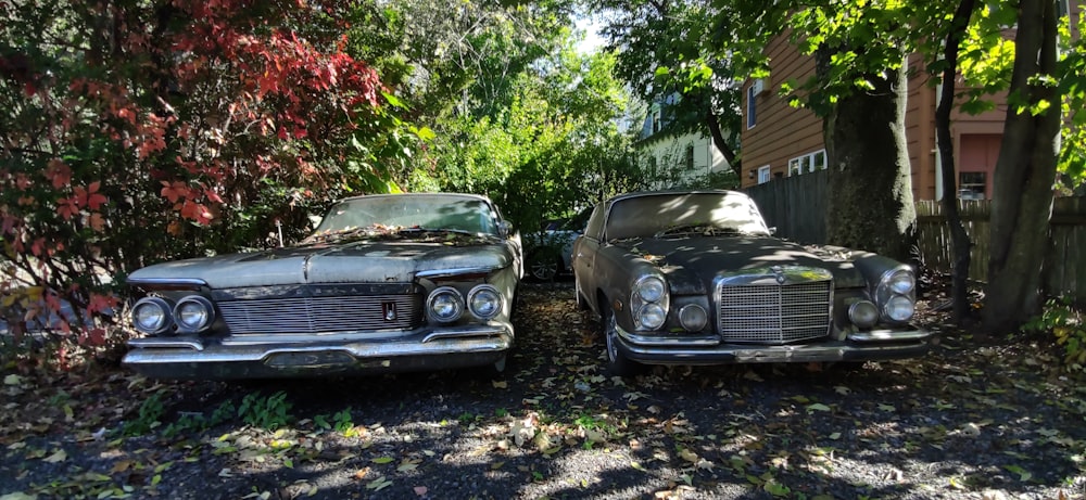 two old cars parked next to each other in a driveway