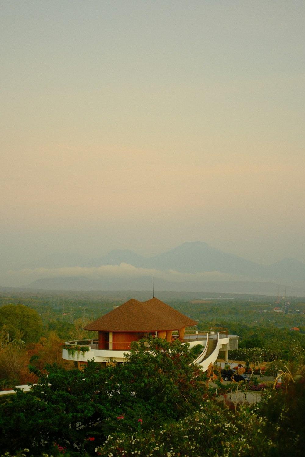 a view of a building with a thatched roof and mountains in the distance
