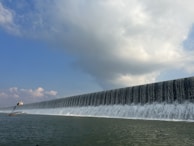 A panoramic view of a large hydroelectric dam with water cascading down.