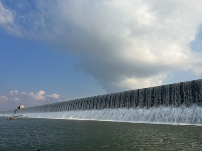 a large wall of water with a boat in the background