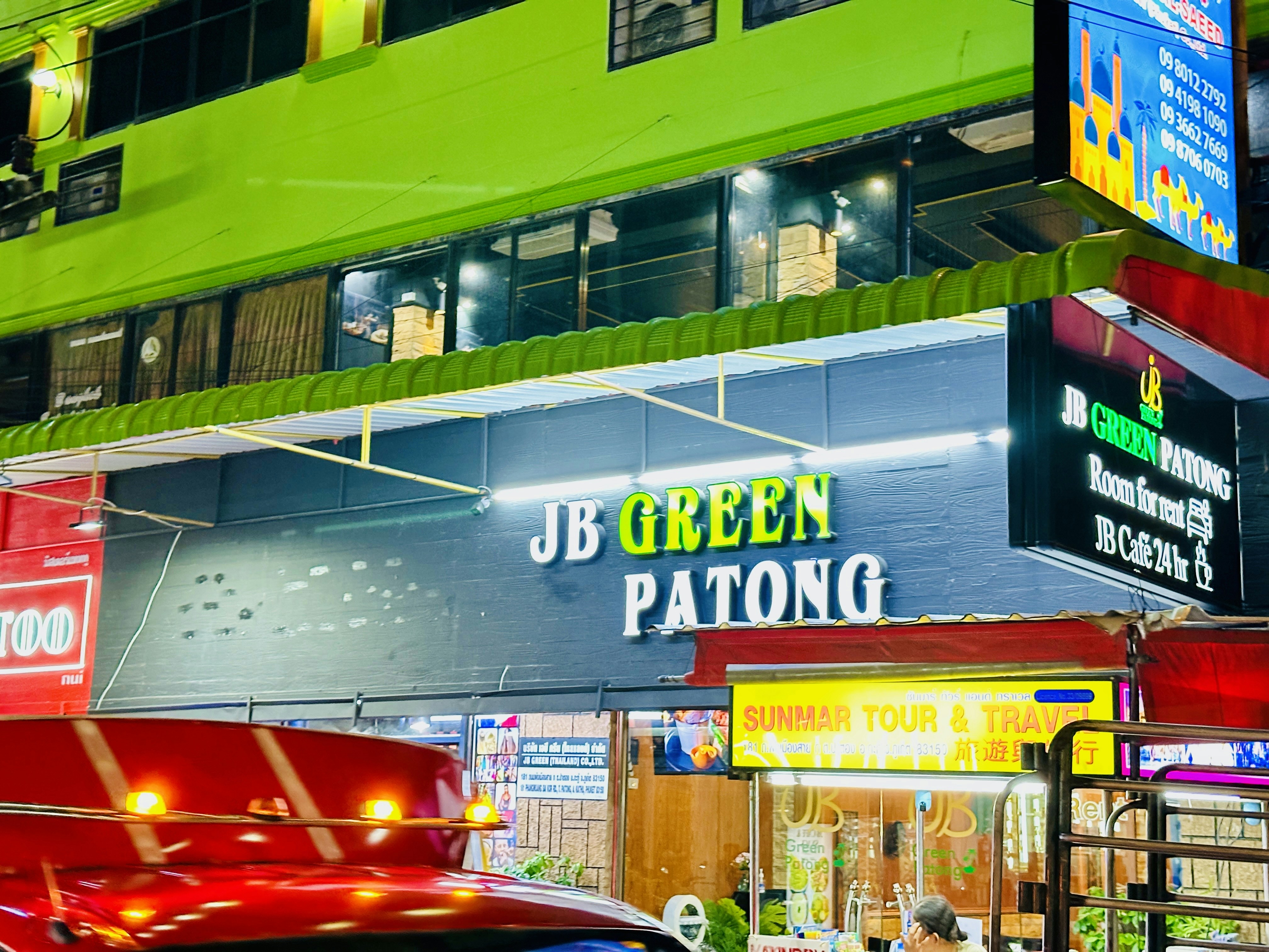 a green building with neon lights and a red car parked in front of it