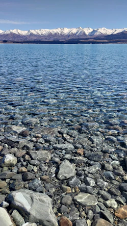 a body of water surrounded by rocks and snow capped mountains