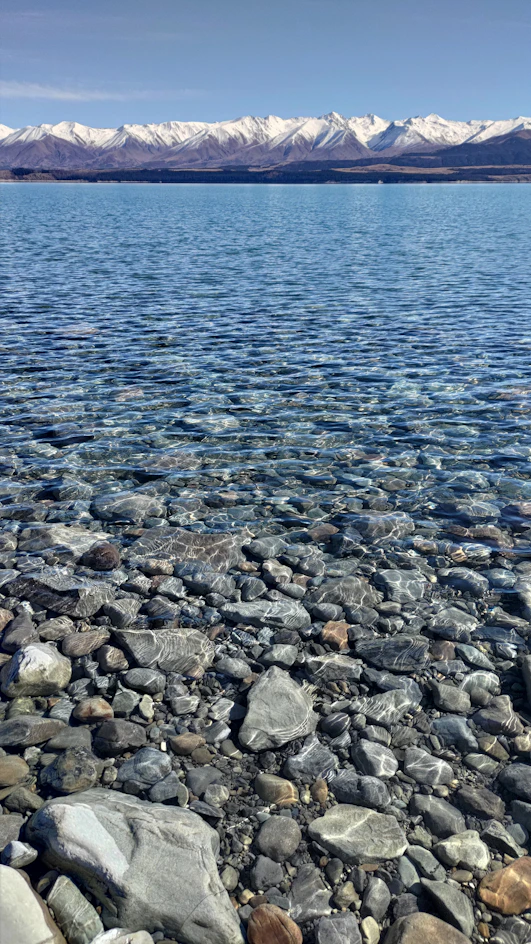 a body of water surrounded by rocks and snow capped mountains