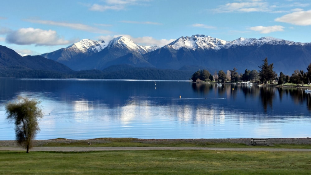 a lake with mountains in the background and a bench in the foreground