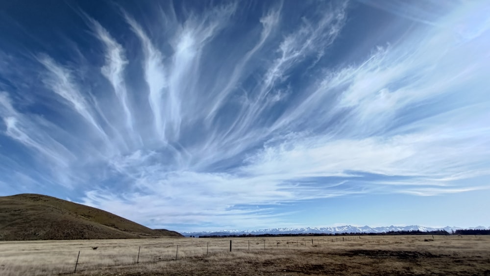 a wide open field with a fence and mountains in the background